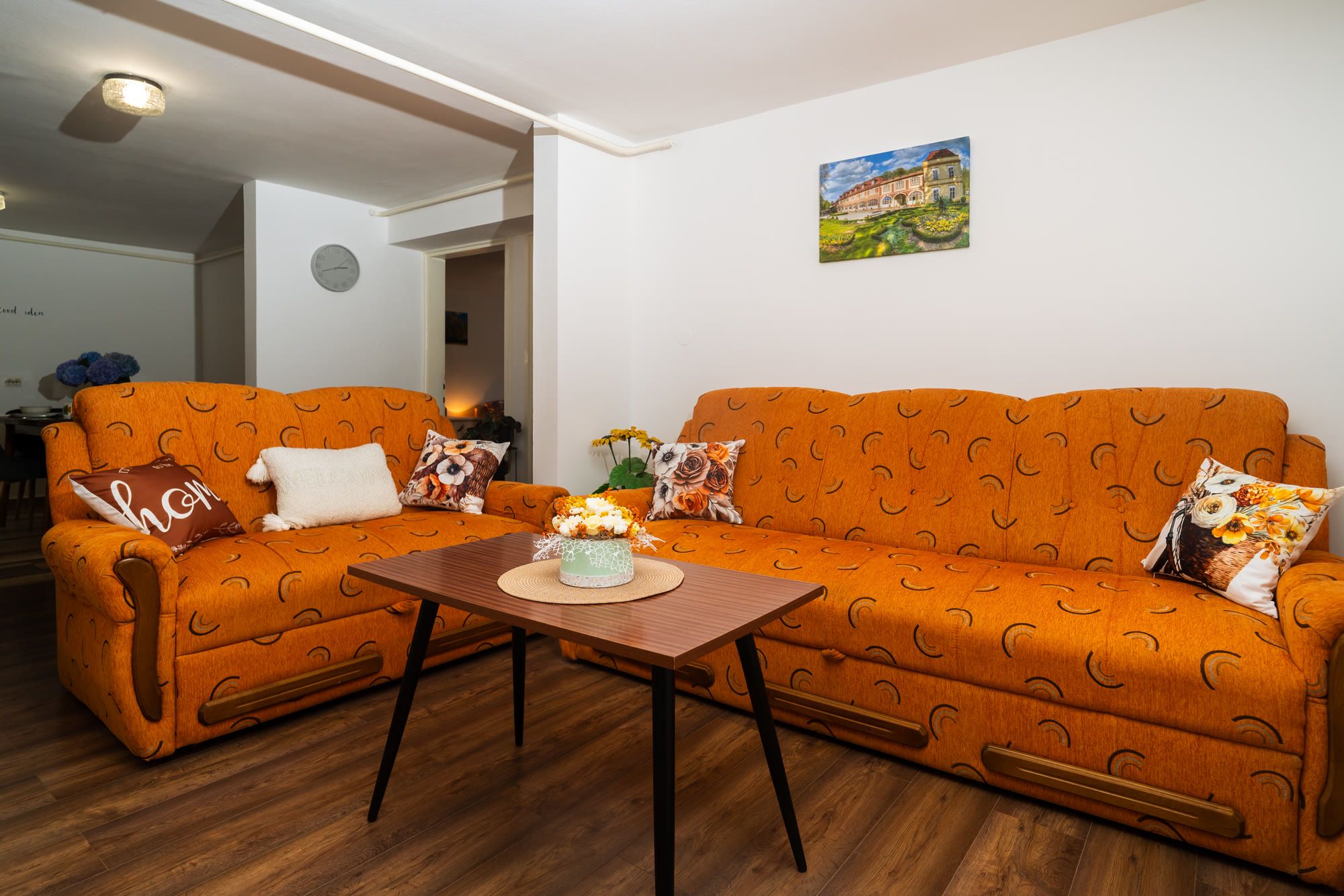 Dnevni boravak s dvije narančaste garniture i slikom daruvarskog dvorca